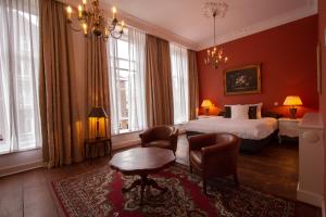 een hotelkamer met een bed, stoelen en ramen bij Hotel Schimmelpenninck Huys in Groningen