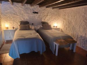 2 camas en una habitación con paredes blancas en Casa Rural LOS PINARES El Juncal de TEJEDA en Tejeda