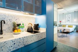 een keuken met blauwe kasten en een kamer met een bed bij Coeo Apart-Hotel Parras in Málaga