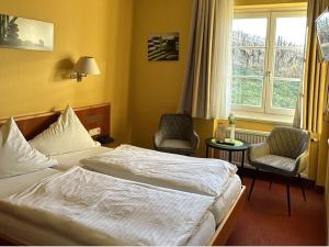 una camera d'albergo con un letto e due sedie e una finestra di Hotel & Restaurant Weinberg a Baden-Baden