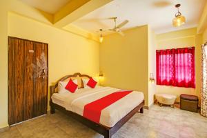 a bedroom with a large bed with red pillows at OYO Shruti Guest House in Goa