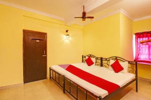 a bedroom with a bed with red pillows on it at OYO Shruti Guest House in Goa