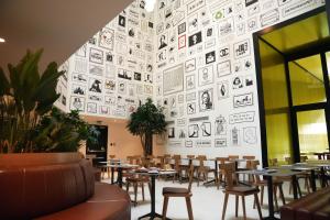a restaurant with tables and chairs and a wall of pictures at SO City Hotel Adults Only in St. Julianʼs