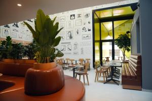 a room with tables and chairs and a potted plant at SO City Hotel Adults Only in St. Julianʼs