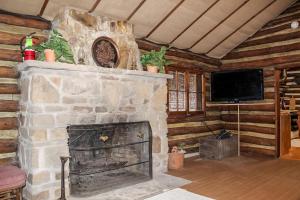 a living room with a stone fireplace with a flat screen tv at Russell Cabin in Logan