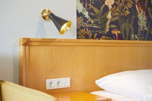 una lámpara en la parte superior de una cama con un cabecero de madera en Hotel Sonneck, en Knüllwald