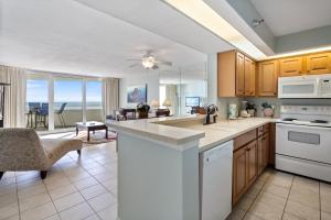 a kitchen with white appliances and a living room at Perdido Sun Resort 704 By Pkrm in Pensacola