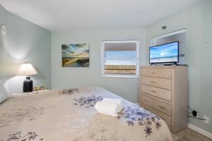 a bedroom with a bed and a dresser with a tv at Perdido Sun Resort 704 By Pkrm in Pensacola +31 photos