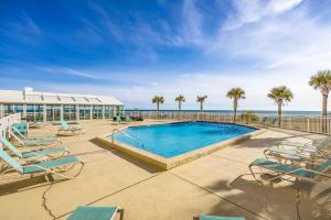 a swimming pool with chairs and the ocean in the background at Perdido Sun Resort 704 By Pkrm in Pensacola