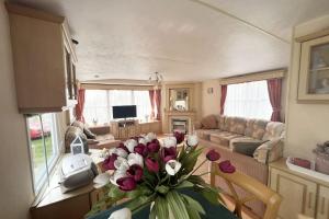 a living room with a vase of flowers on a table at Knus chalet, De Nollen P12 in Callantsoog