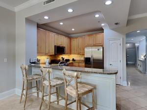 a kitchen with wooden cabinets and a island with bar stools at Adagio 203E in Santa Rosa Beach
