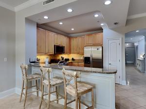 a kitchen with wooden cabinets and a island with bar stools at Adagio #203E in Santa Rosa Beach +29 photos