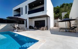 ein Haus mit einem Pool, 2 Stühlen und Sonnenschirmen in der Unterkunft Cozy Home In Dramalj With House Sea View in Dramalj