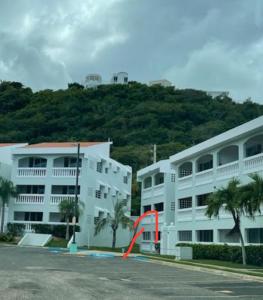 un edificio de apartamentos blanco con un objeto naranja delante en Beachfront Studio Apt w/ Full Kitchen & Pool, en Isabela