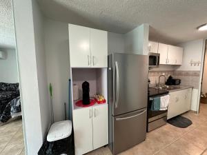 a kitchen with white cabinets and a stainless steel refrigerator at Beachfront Studio Apt w/ Full Kitchen & Pool in Isabela