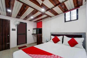 1 dormitorio con 1 cama con almohadas rojas y blancas en OYO The Mid Town Inn, en Patna