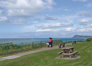 フィッシュガードにあるFishguard Holiday Parkの海を眺めながらのピクニックテーブルの横に立つ二人