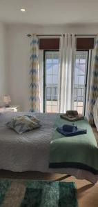 a bedroom with a large bed with two windows at Casa Isa in Almograve