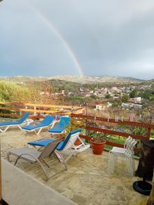 een groep stoelen op een patio met een regenboog op de achtergrond bij Despina country retreat in Paphos City