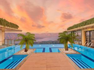 a pool with palm trees and a view of the mountains at The Cliff Resort & Spa, Panchgani in Panchgani