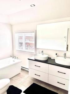 a bathroom with two sinks and a tub and a toilet at Chalet les jasmins Orford in Orford