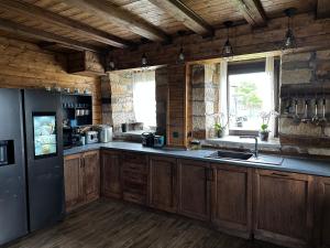 a kitchen with wooden cabinets and a black refrigerator at Къща за гости ,,Горски полъх” 