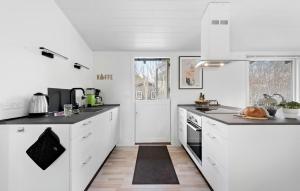 a kitchen with white cabinets and black counter tops at Beautiful Home In Dronningmølle in Dronningmølle +13 photos
