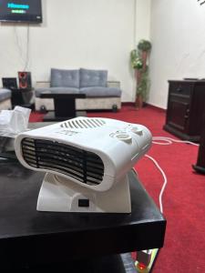 a white fan sitting on a table in a living room at Islamabad lodges apartment suite in Islamabad