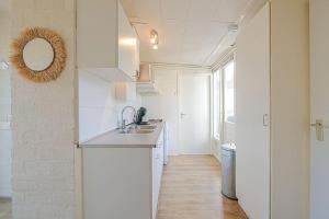 - une cuisine blanche avec un évier et un miroir dans l'établissement Vakantiehuis Duinland 251 aan zee, park Duinland, à Sint Maartensvlotbrug