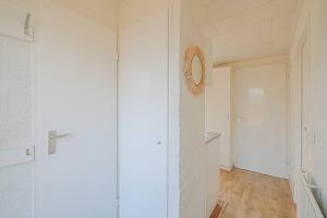 Cette chambre dispose d'un couloir avec des murs blancs et une porte. dans l'établissement Vakantiehuis Duinland 251 aan zee, park Duinland, à Sint Maartensvlotbrug