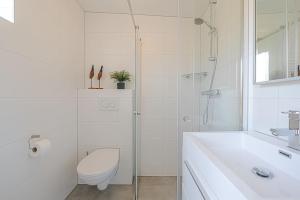 a white bathroom with a toilet and a sink at Duinland 251 - Park Duinland Sint Maartenszee in Sint Maartensvlotbrug