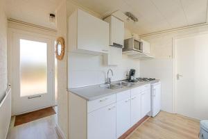 a kitchen with white cabinets and a sink at Duinland 251 - Park Duinland Sint Maartenszee in Sint Maartensvlotbrug