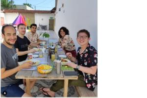 Eine Gruppe von Menschen, die an einem Tisch sitzen und Essen essen. in der Unterkunft LETICIAS GUEST HOUSE in Leticia