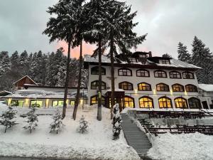 a large building with trees in the snow at Cerbul Chalét Accommodation & Wellness in Râşnov