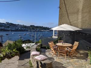 a patio with a table and chairs and an umbrella at 3 Bed in Polruan PC009 in Fowey