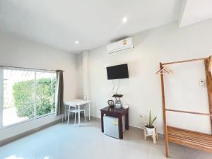 a room with a tv and a table and a window at On Green Resort in Ban Huai Sua