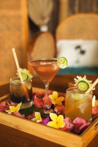 een dienblad met twee cocktails en bloemen op een tafel bij Villa Tokay - Luxury Private Villas in Gili Air