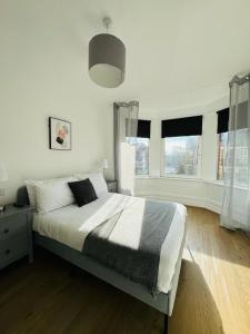 een slaapkamer met een groot bed en 2 ramen bij Pearl House - Delightful 3-4 Bedroom Coastal Getaway in Gorleston-on-Sea