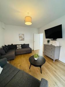 a living room with a couch and a flat screen tv at Pearl House - Delightful 3-4 Bedroom Coastal Getaway in Gorleston-on-Sea