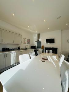 uma cozinha com uma mesa branca e cadeiras brancas em Pearl House - Delightful 3-4 Bedroom Coastal Getaway em Gorleston-on-Sea