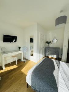 a white bedroom with a bed and a tv on the wall at Pearl House - Delightful 3-4 Bedroom Coastal Getaway in Gorleston-on-Sea