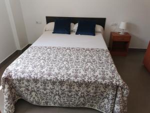 1 cama con manta blanca y negra y almohadas azules en Casa en Bassetes LOCDENIA, en El Verger