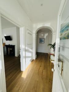 Habitación con un pasillo con suelo de madera y paredes blancas. en Pearl House - Delightful 3-4 Bedroom Coastal Getaway en Gorleston-on-Sea