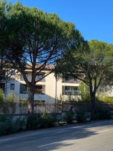 ein weißes Gebäude mit Bäumen vor einer Straße in der Unterkunft Escapade Uzétienne Cœur de ville et Parking in Uzès