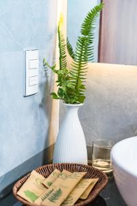a white vase with a plant on a table at Khe Sanh Luxury Hotel in Hương Hóa