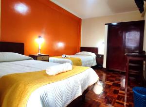2 camas en una habitación de hotel con paredes de color naranja en Hotel Express, en La Paz