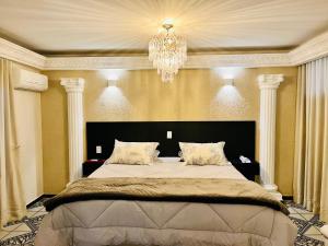 レジストロにあるHotel Estoril Garden & Restauranteのシャンデリア付きの大きなベッドのある寝室
