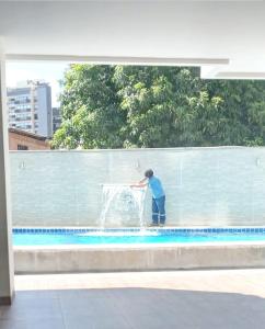 un hombre está jugando en una fuente en una piscina en Downtown Apartments "Altos del Sur" en Santa Cruz de la Sierra
