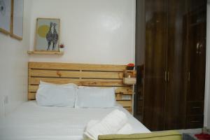 a bed with a wooden headboard and white pillows at Enn lovely apartment 10 in Bungoma