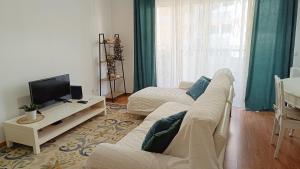 salon z białą kanapą i telewizorem w obiekcie Refúgio Garajau Madeira w Caniço